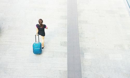 High angle view of woman with luggage walking on street