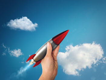 Low angle view of person hand against blue sky