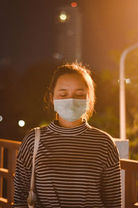 Young woman wearing pollution mask at night