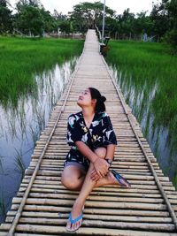 Young woman sitting on pier over lake