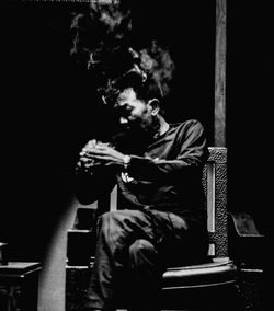 Man holding cigarette while sitting on chair