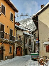 Snow covered houses by buildings against sky