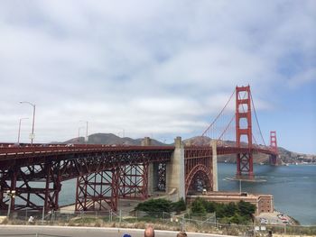 Suspension bridge against cloudy sky