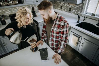 Man and woman couple stand together in kitchen making coffee