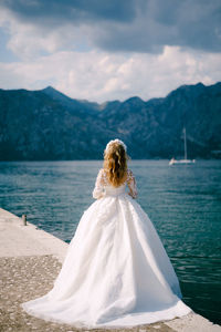 Rear view of bride standing by lake