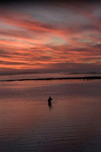 Scenic view of sea against cloudy sky at sunset