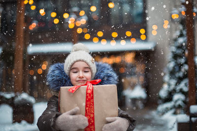 Portrait of smiling girl holding present standing outdoors