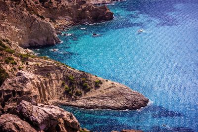 High angle view of rocks at shore against blue sky