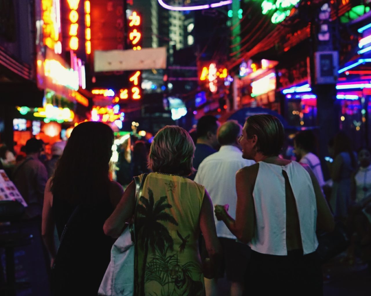 REAR VIEW OF PEOPLE ON ILLUMINATED STREET