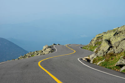 Road leading towards mountains against sky