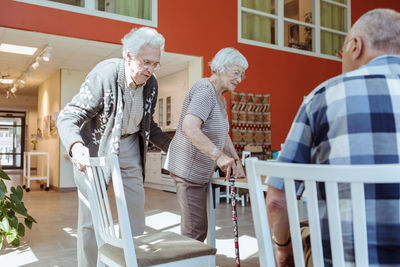 Senior man pulling chair out for woman in nursing home