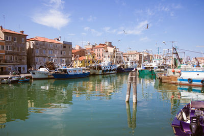 Boats moored in canal against buildings in city