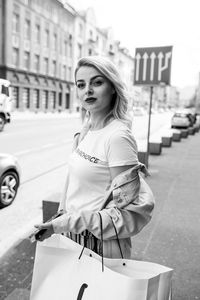 Portrait of beautiful woman with shopping bags standing on street in city