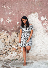 Full length portrait of a young woman in summer dress, smiling, looking down, hair, hairstyle.