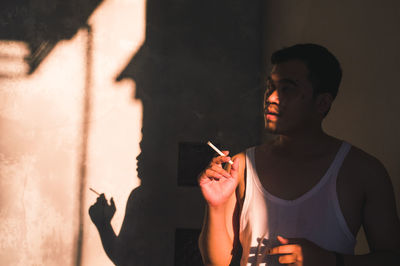 Young man holding cigarette at home