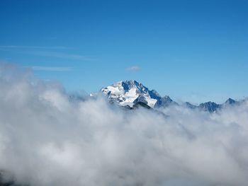 Low angle view of snow mountains against clear blue sky