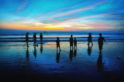 Silhouette children enjoying at beach during sunset
