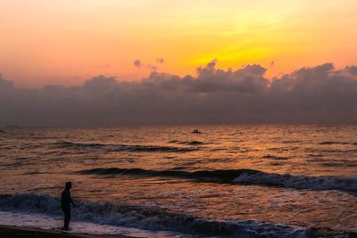 Silhouette person standing on beach against sky during sunset