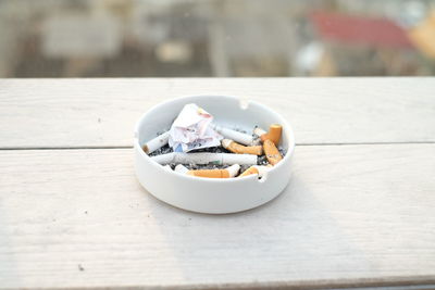 Close-up of cigarette butts in ashtray on table