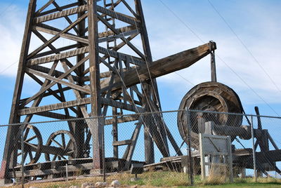 Low angle view of old metallic structure on field against sky