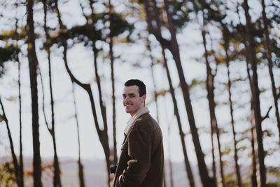 Portrait of smiling man standing against trees