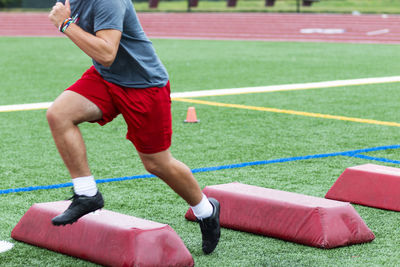 Low section of man running over barriers at sports track