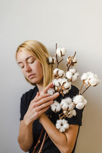A woman with a bunch of cotton plant twigs in her hands.