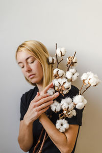 Beautiful young woman holding flowers against white background