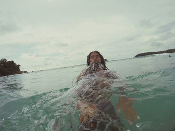 Man swimming in sea against sky