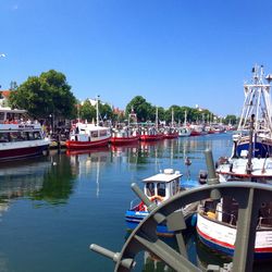 Boats moored at harbor against clear sky