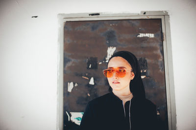 Portrait of young man looking away while standing against window