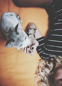 Cropped image of young woman with cat resting on bed