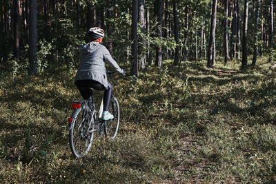 Active woman cycling on forest road. female riding bicycle off-road route on summer vacation day