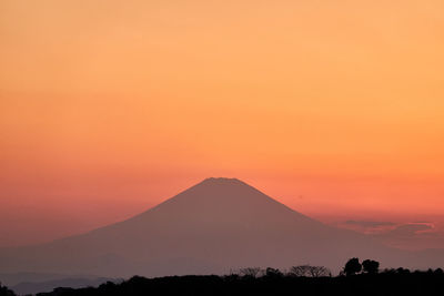 Scenic view of silhouette mountains against orange sky