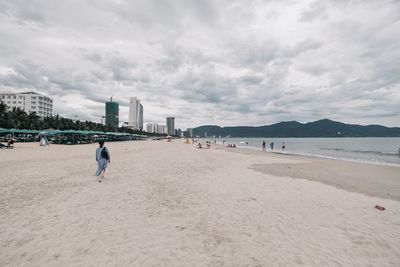 People on beach against sky in city