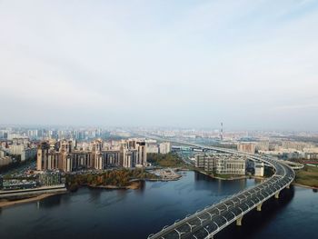 Bridge over river amidst buildings in city against sky