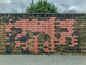 Brick wall by building against sky