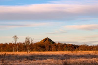 Built structure on field against sky at sunset