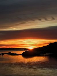 Scenic view of sea against dramatic sky during sunset