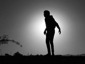 Silhouette man standing on field against sky at night