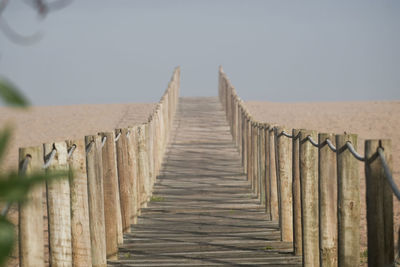 Wooden posts on fence against clear sky