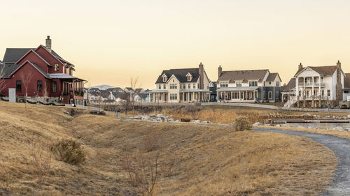 Houses on field by buildings against clear sky