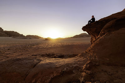 Man on rock against sky during sunset. shoted in the wadi rum desert, jordan. 