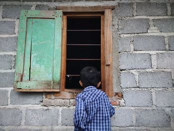 Rear view of boys standing against wall