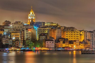 River against illuminated galata tower amidst buildings at night