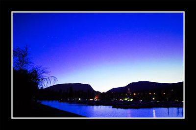 Scenic view of lake against clear blue sky at night