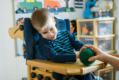 Boy looking at toy while sitting at home