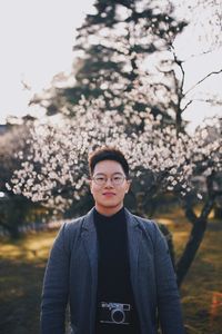 Portrait of young man standing against trees