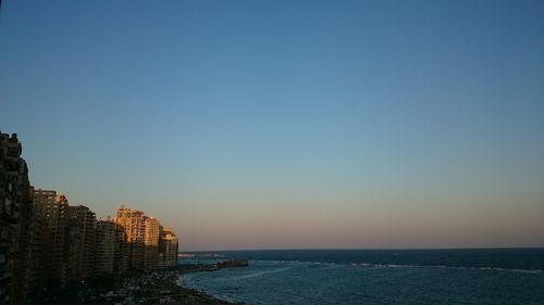 Scenic view of sea by buildings against clear sky