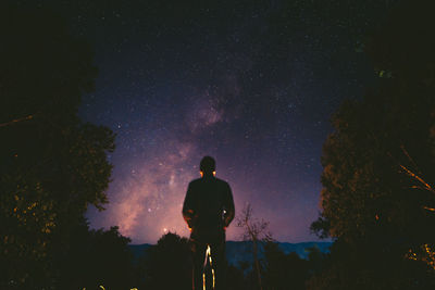 Rear view of man standing against sky at night